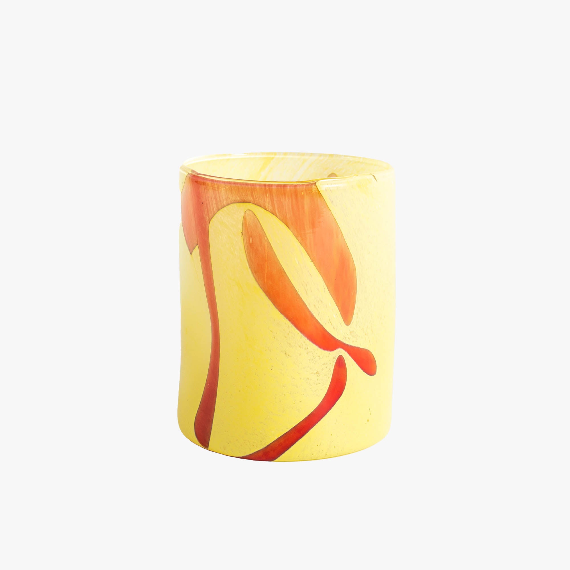 A handblown yellow glass tumbler with red swirl patterns.