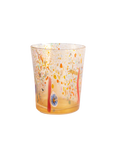 A clear glass tumbler with a warm amber base and multicolored hand-blown speckles in orange, yellow, red, and blue, isolated on a white background.