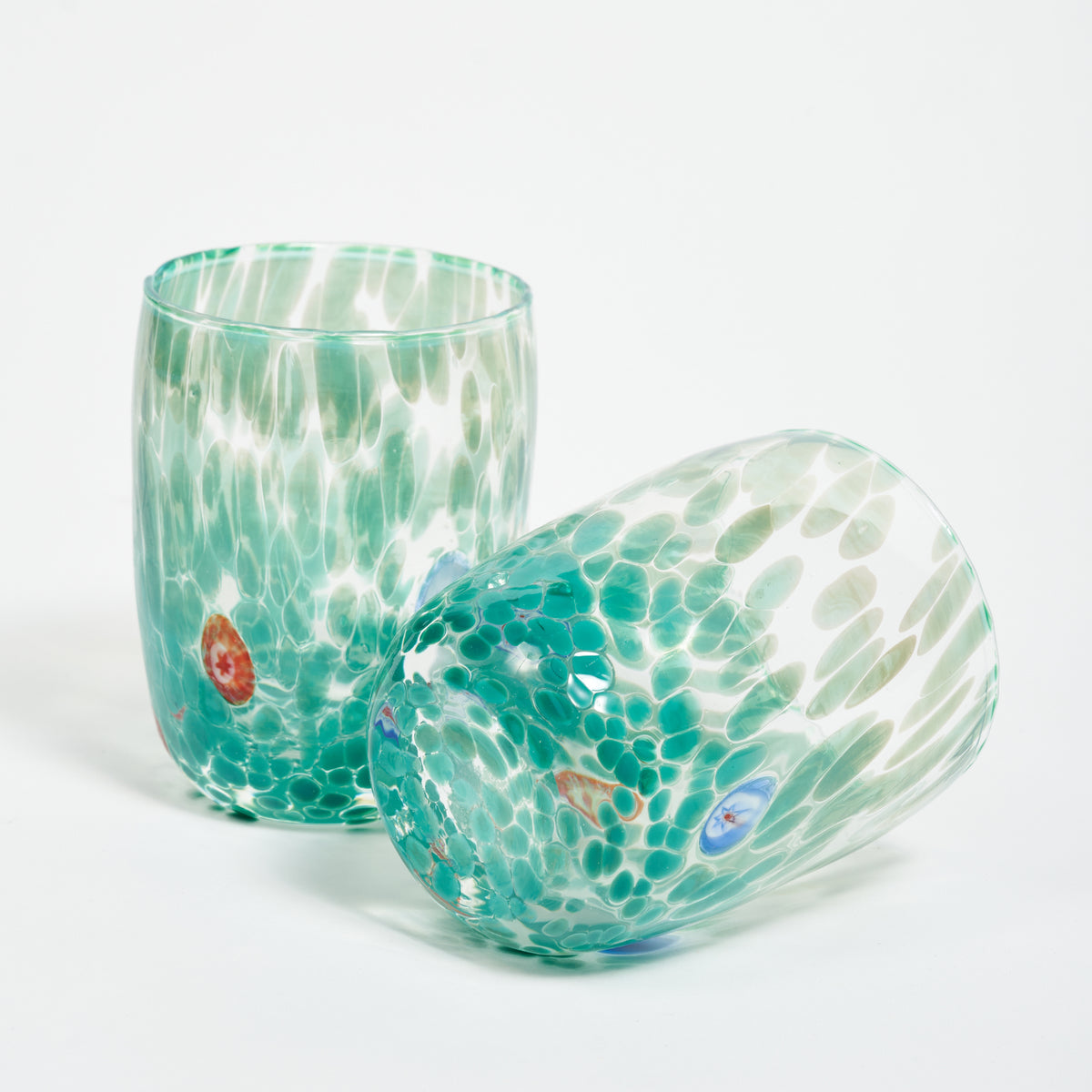 Two Murano glass tumblers with a speckled green pattern and multicolored accents.